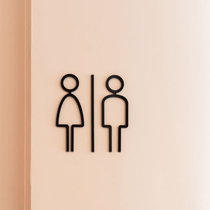 Minimal black restroom icon sign with men and women symbols on wall
