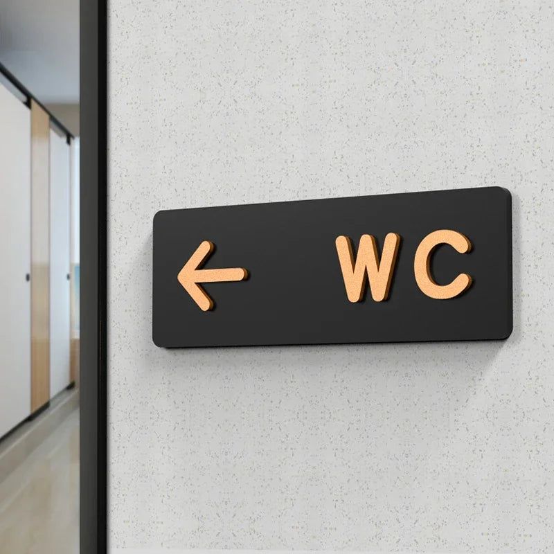 Modern WC direction sign with left arrow in black and gold finish
