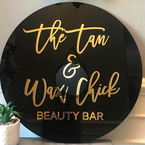 The Tan and Wax Chick round acrylic sign black board gold script 3D salon logo beauty bar signage